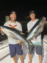 Two anglers holding freshly caught blackfin tuna during a nighttime offshore fishing charter out of Sarasota, Florida.