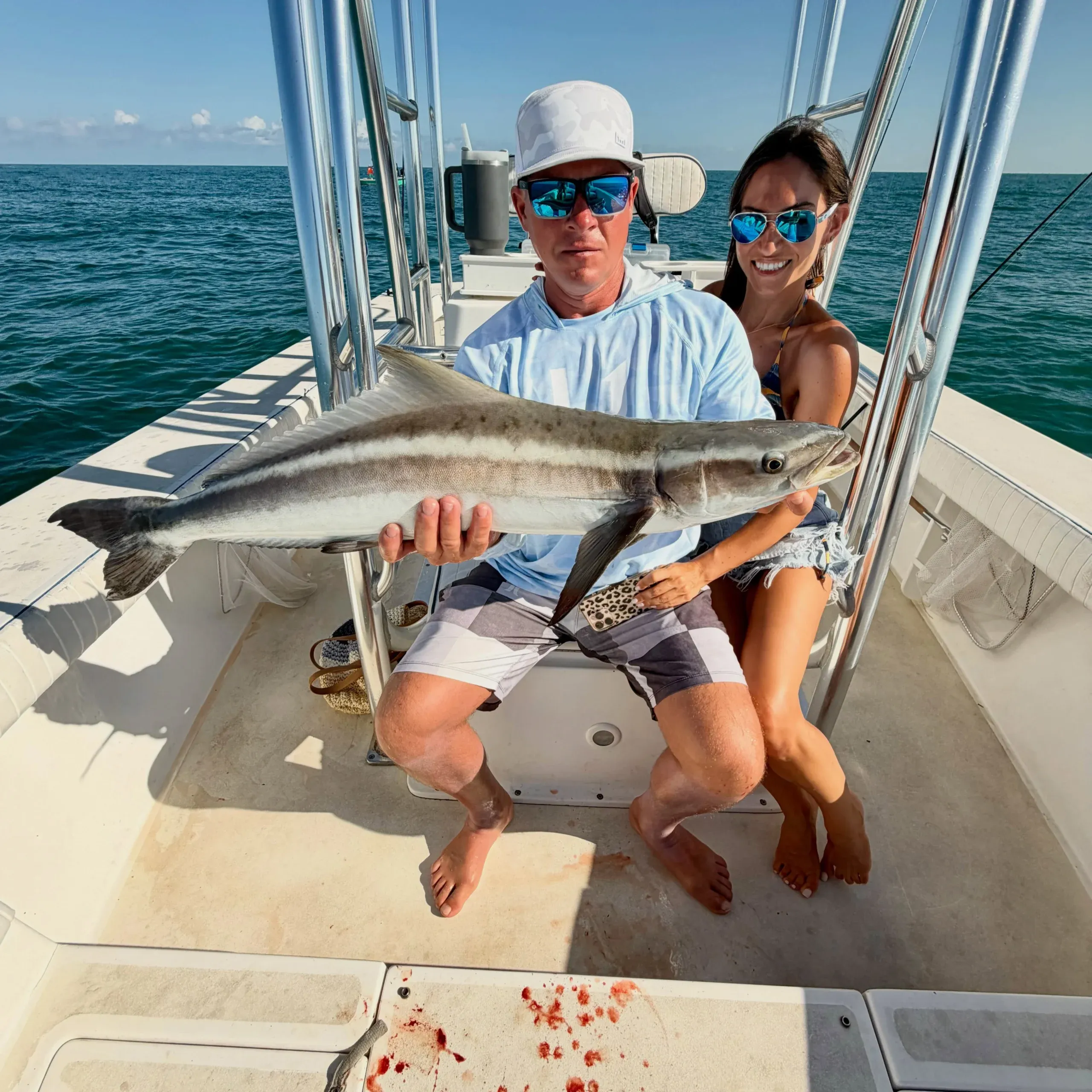 Couple holding a large cobia aboard a Sarasota fishing charter boat on calm Gulf waters.