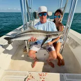 Couple holding a large cobia aboard a Sarasota fishing charter boat on calm Gulf waters.