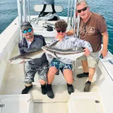 Family proudly holding two cobia aboard a Sarasota fishing charter boat after a successful day on the Gulf.