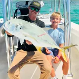 Captain and young angler holding a large African pompano during a Sarasota nearshore fishing charter.