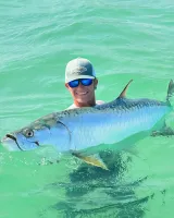Angler holding a healthy silver tarpon in the clear waters of Sarasota Bay during a catch-and-release fishing charter.
