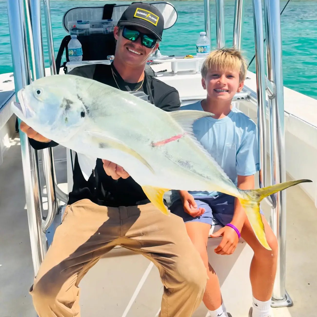Family fishing trip with father and son holding a trophy African pompano in Sarasota, Florida.