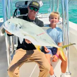 Family fishing trip with father and son holding a trophy African pompano in Sarasota, Florida.
