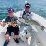 Young angler and captain holding a sea trout and snook during a Sarasota family fishing charter.