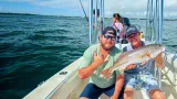 Anglers holding a redfish during a Sarasota inshore fishing charter.