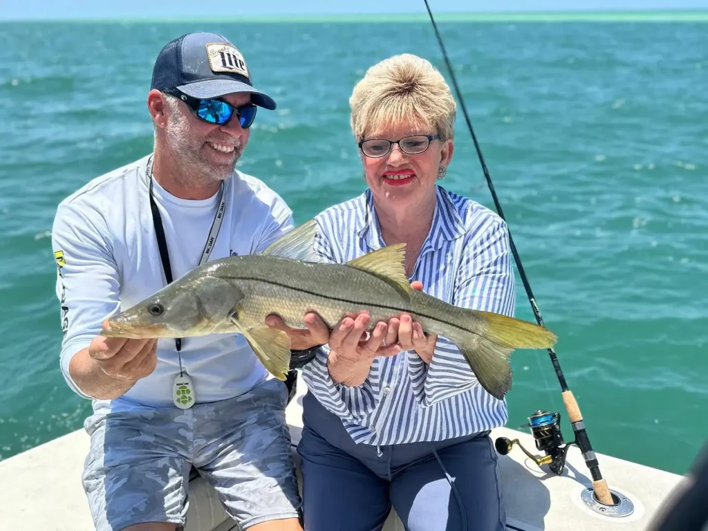 Couple holding a snook during a Sarasota fishing charter.