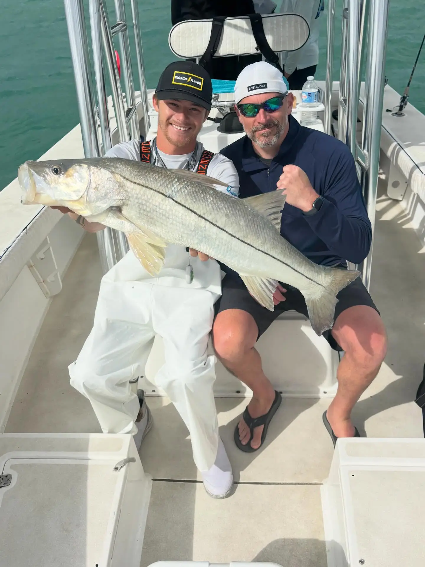 Anglers holding a large snook aboard a Sarasota fishing charter boat.