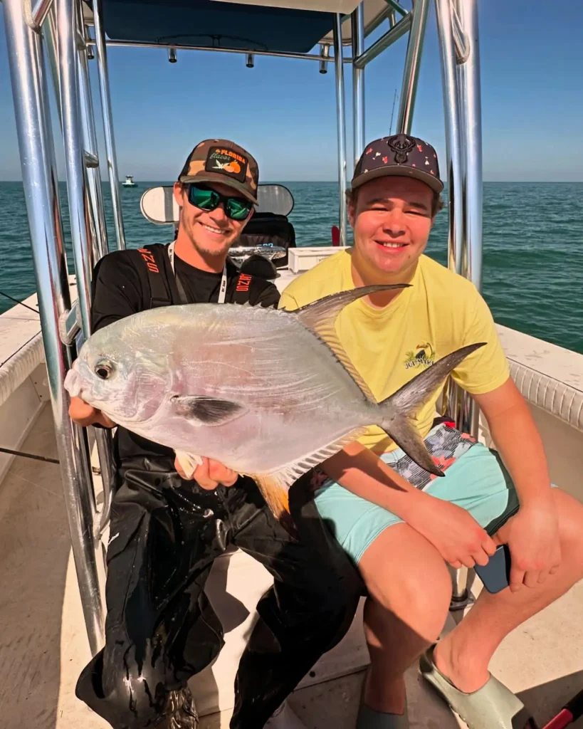 Two anglers holding a permit during a Sarasota fishing charter.