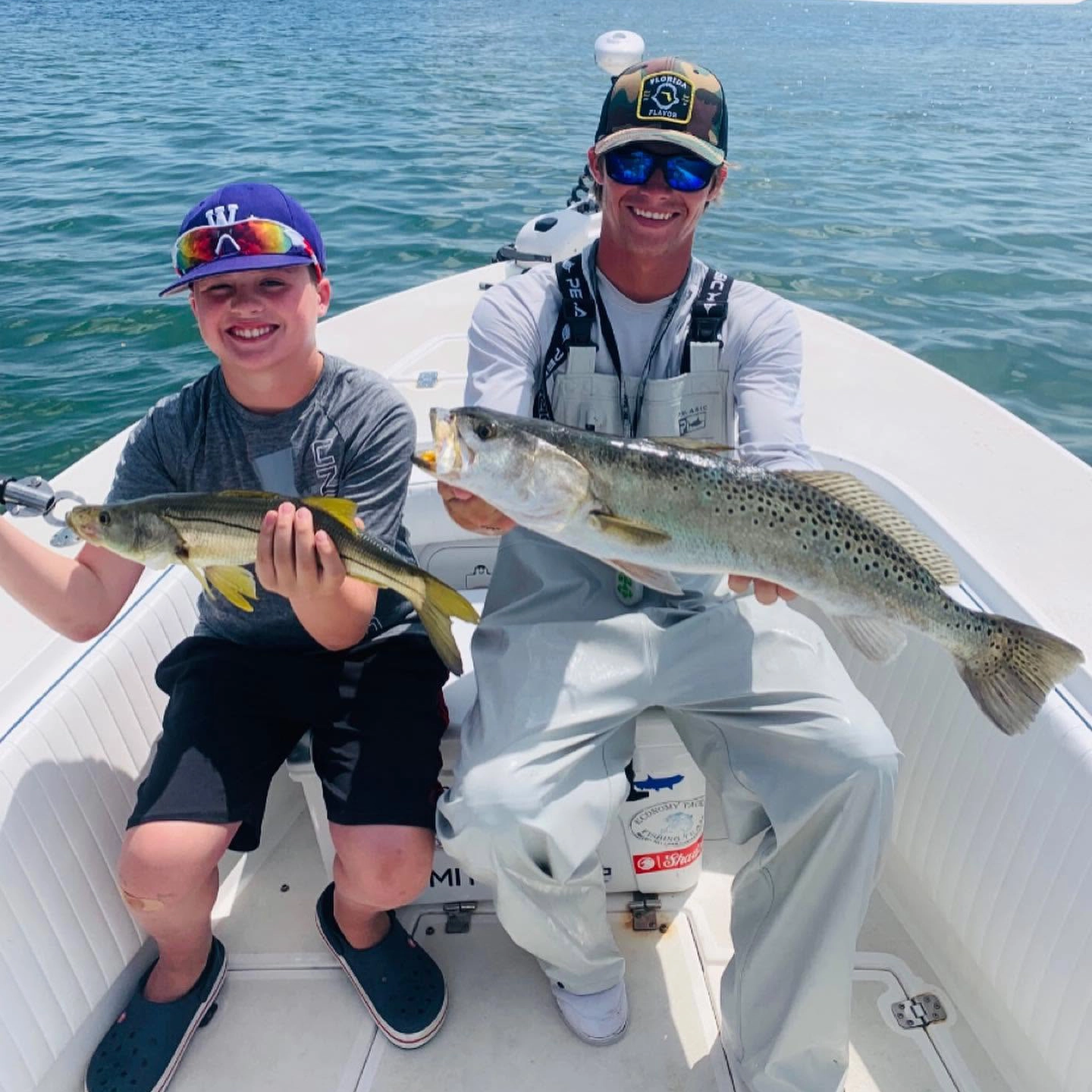 Young angler and captain holding a sea trout and snook during a Sarasota family fishing charter.