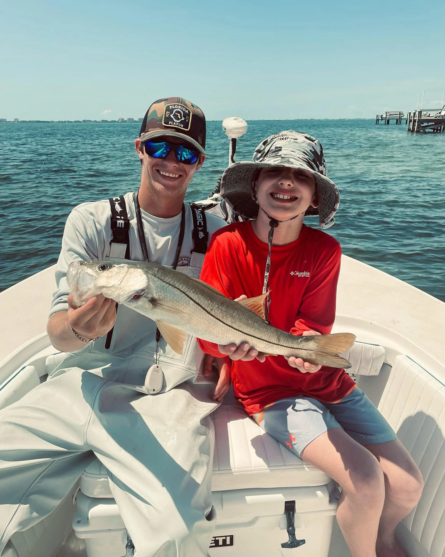 Young angler and captain holding a snook during a Sarasota family fishing charter.