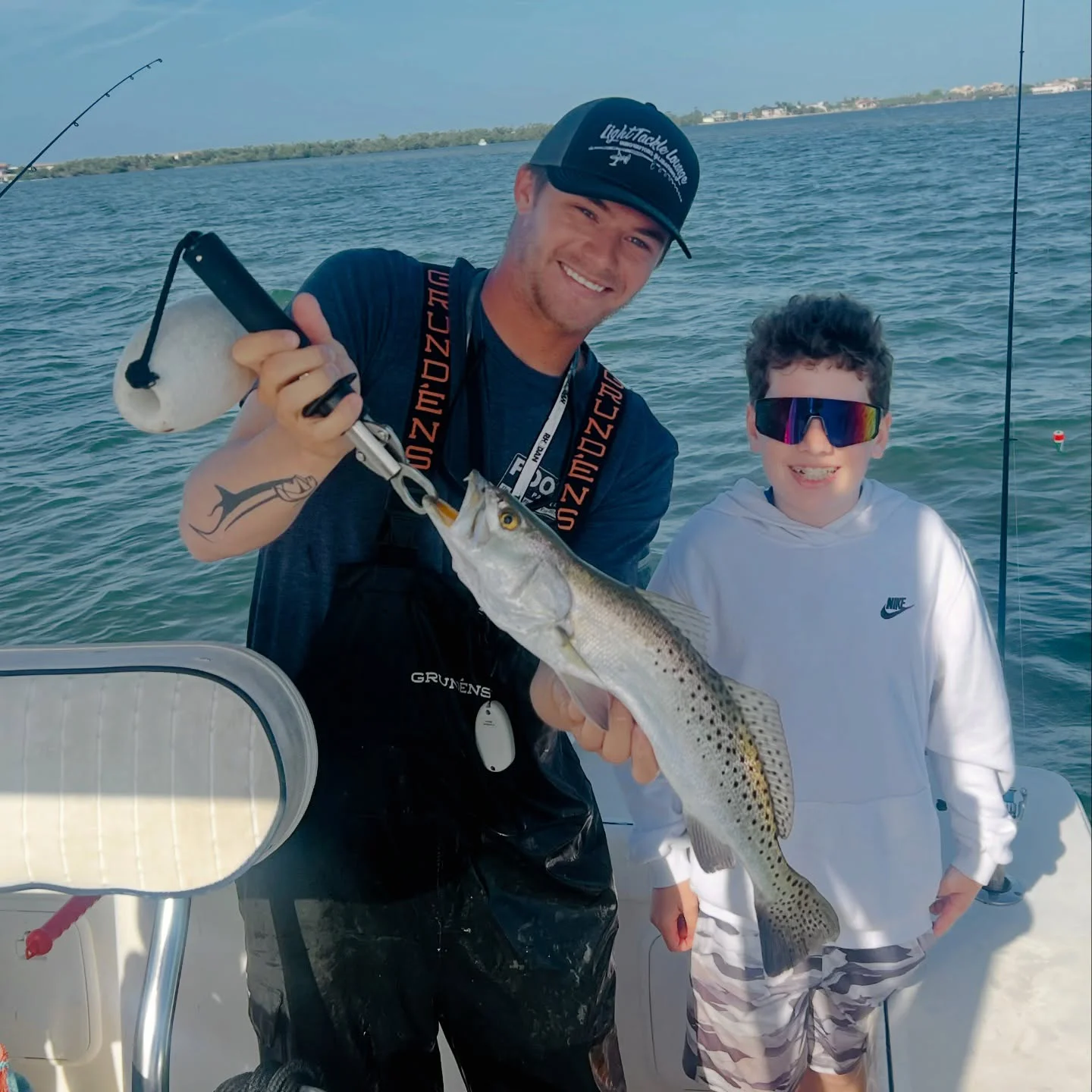 Young angler and captain holding a speckled sea trout during a Sarasota family fishing charter.