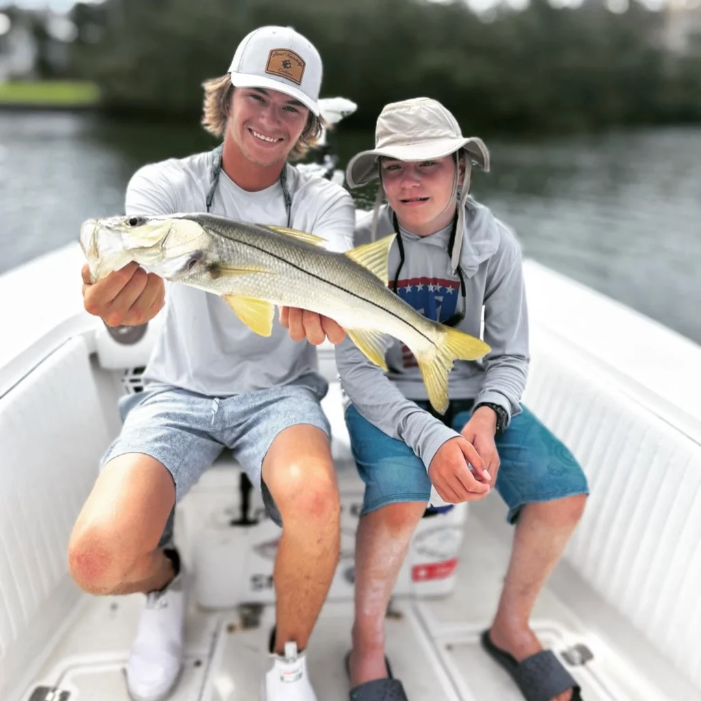 Young anglers holding a snook during a Sarasota family fishing charter.