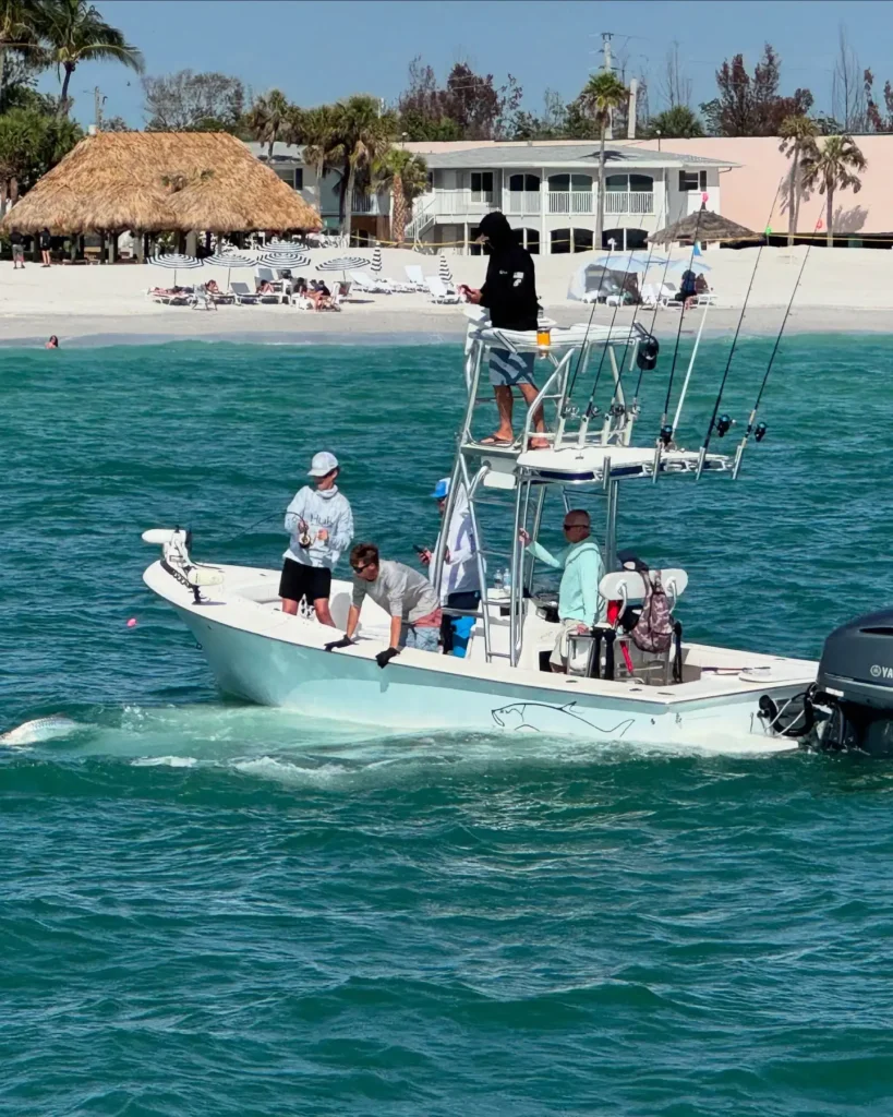 Sarasota fishing charter boat with anglers searching for tarpon along the beach.