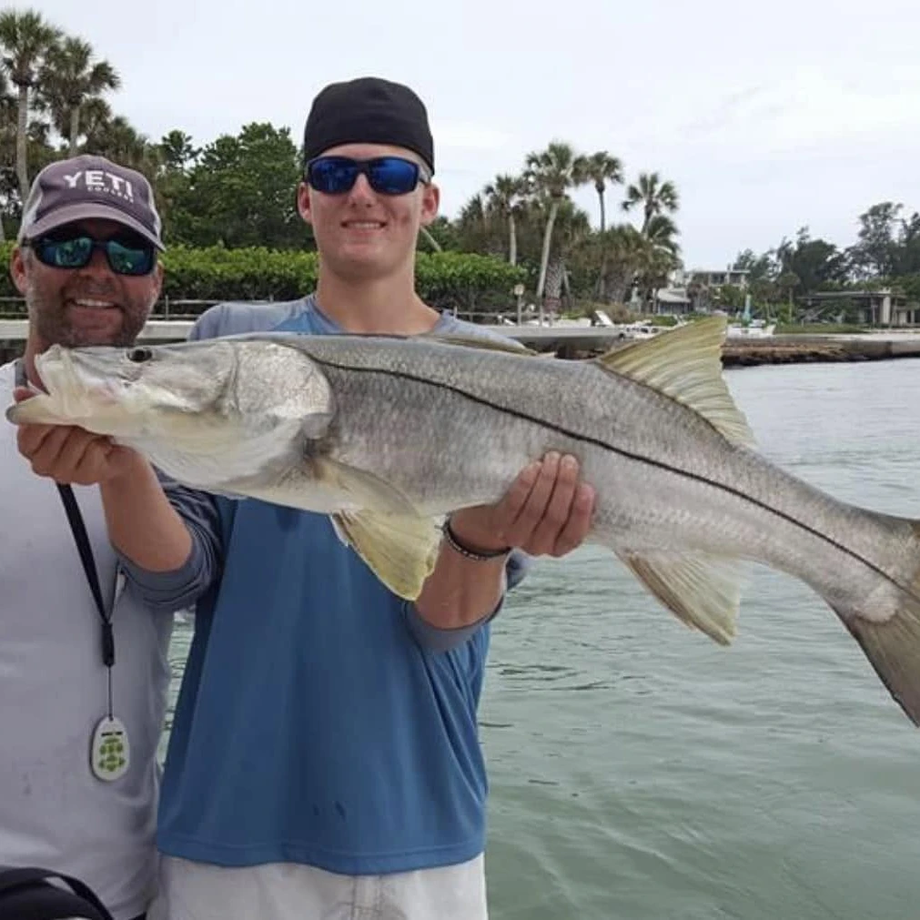 Young angler holding a trophy snook after a successful Sarasota fly fishing charter.