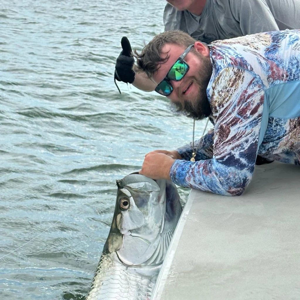 Angler releasing a trophy tarpon beside the boat during a Sarasota fly fishing charter.