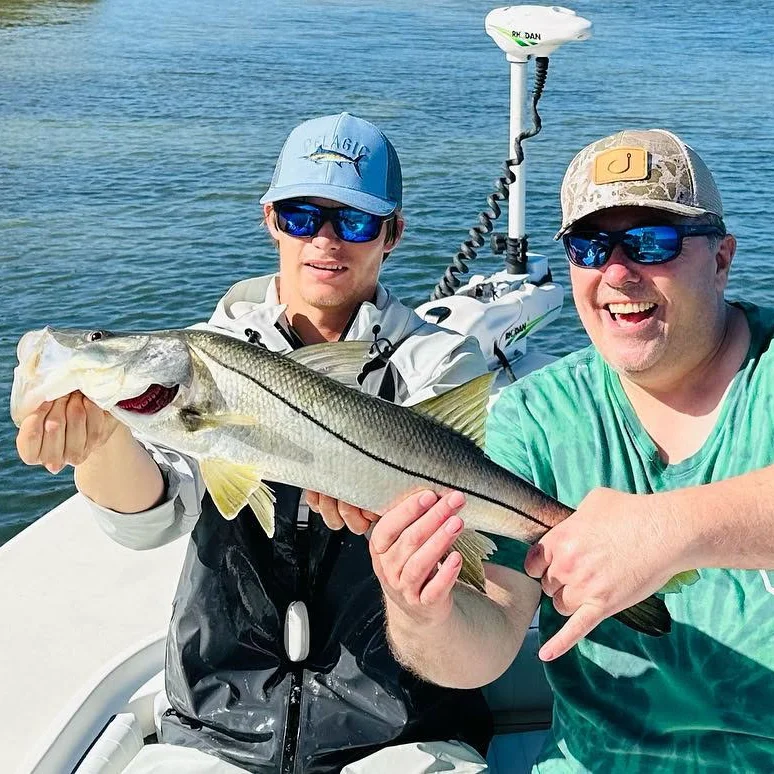 Two friends holding a snook during a Sarasota inshore fishing charter.