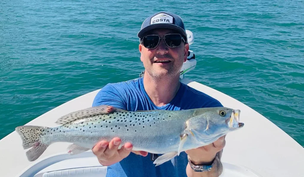 Angler holding a spotted seatrout during a Sarasota inshore fishing charter.