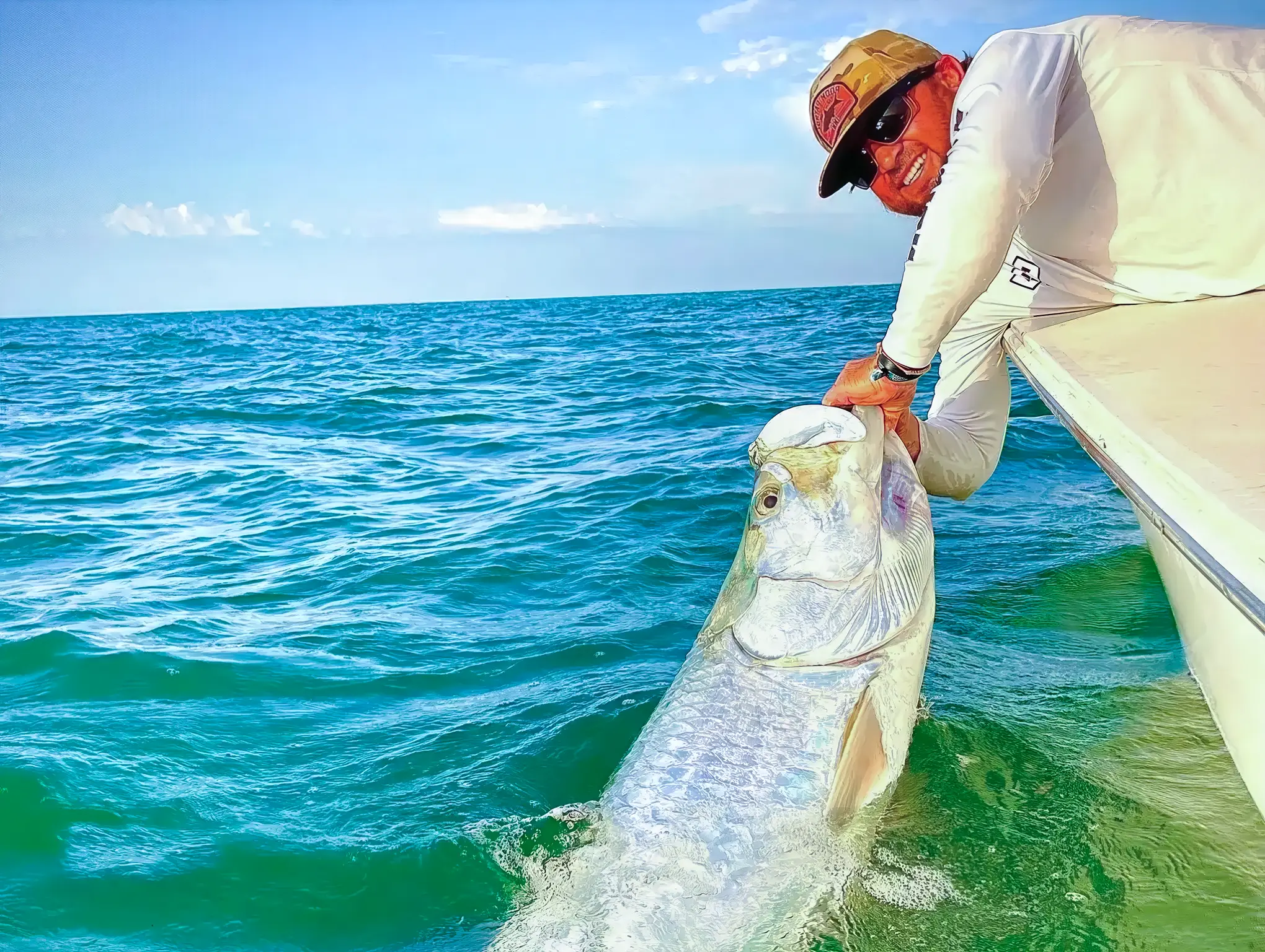 Captain releasing a giant tarpon beside the boat during a Sarasota tarpon fishing charter.