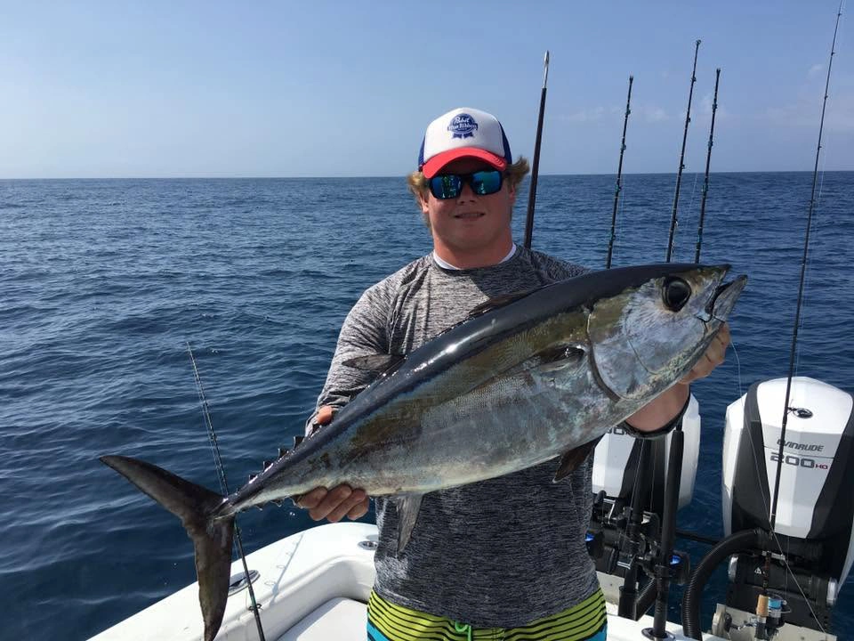Young angler holding a large blackfin tuna aboard a Sarasota fishing charter boat in the Gulf of Mexico.