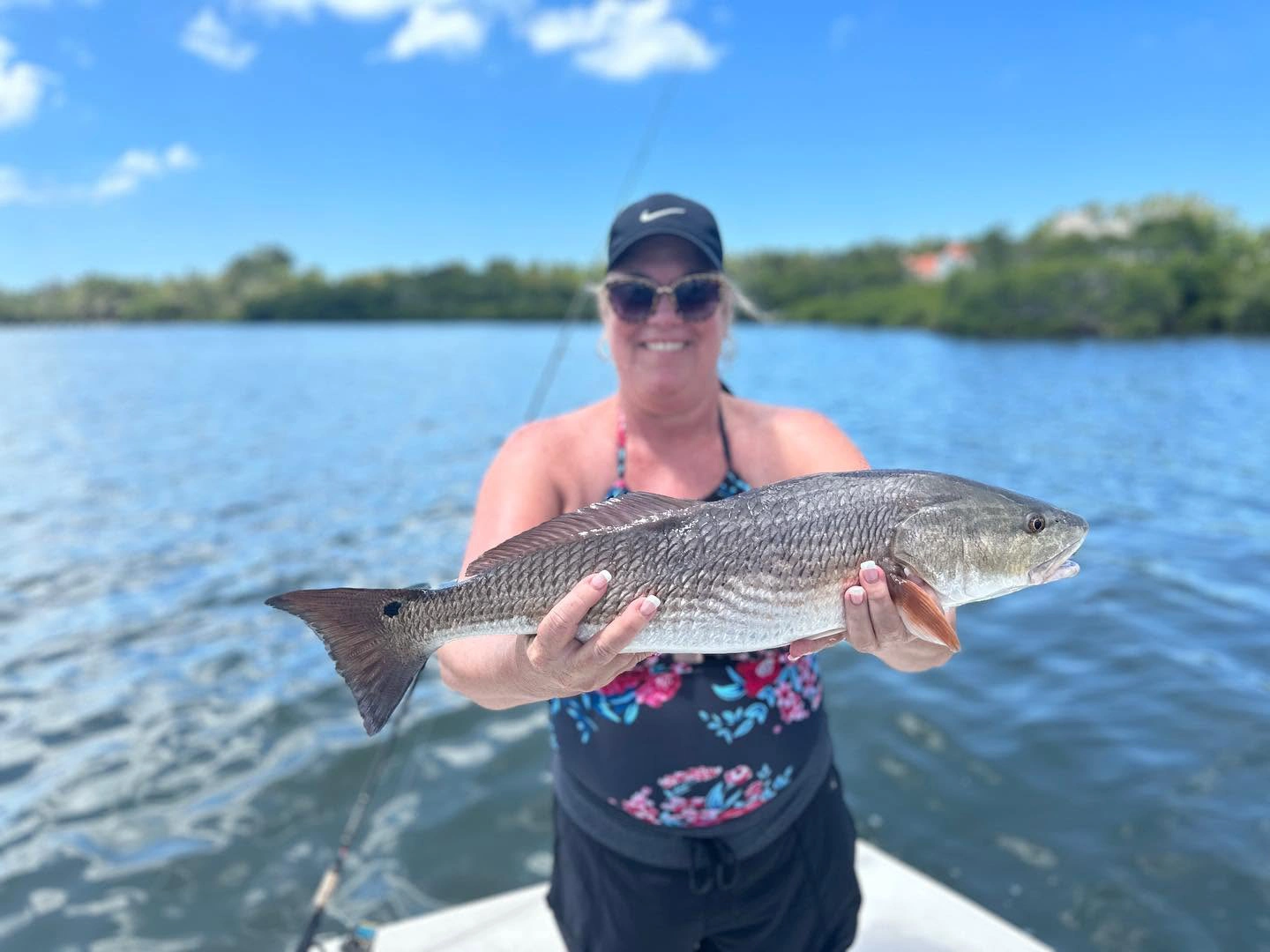 Angler smiling while holding a large redfish aboard a Sarasota fishing charter boat on calm inshore waters.