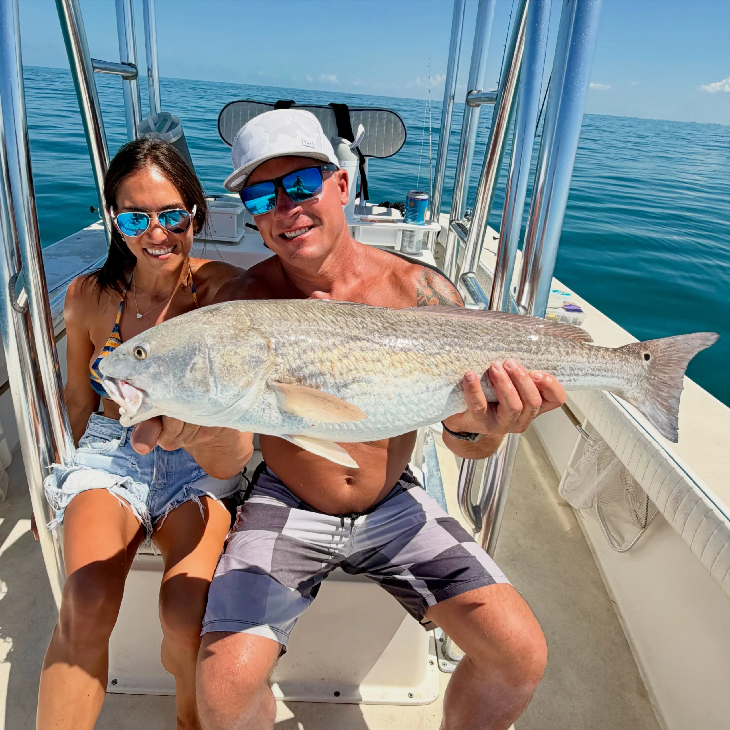 Couple holding a large redfish aboard a Sarasota fishing charter boat on calm Gulf waters.