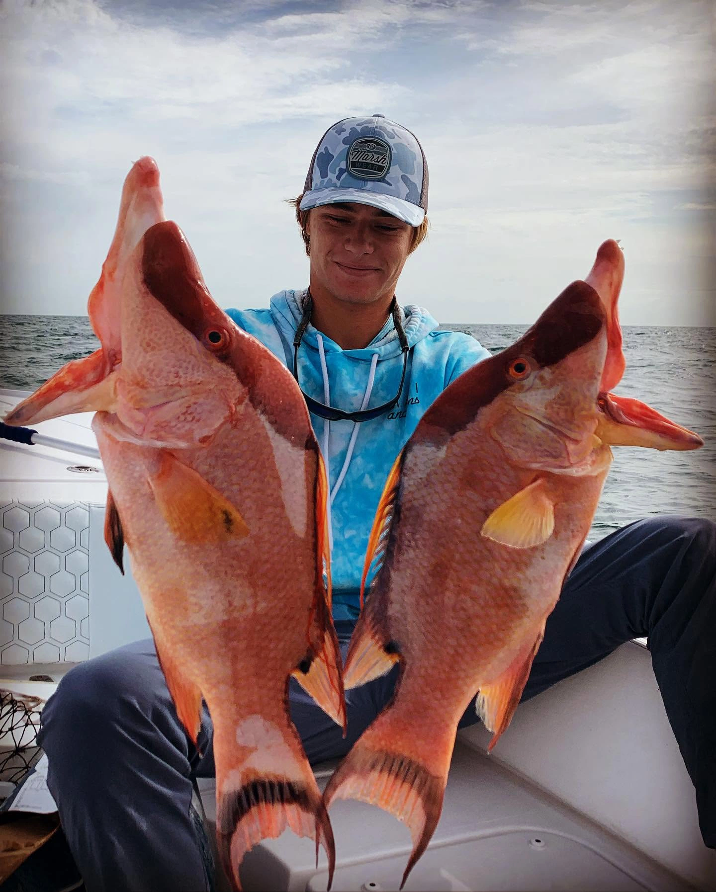 Young angler holding two gray triggerfish caught during an offshore fishing charter in the Gulf of Mexico near Sarasota, Florida.