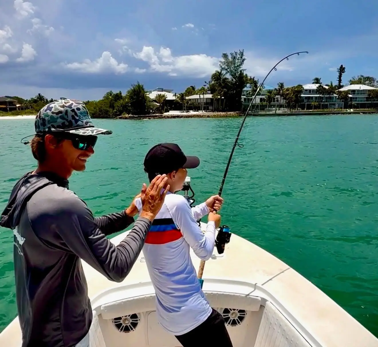 Young angler fighting a fish with guidance from the captain during a Sarasota family fishing charter.